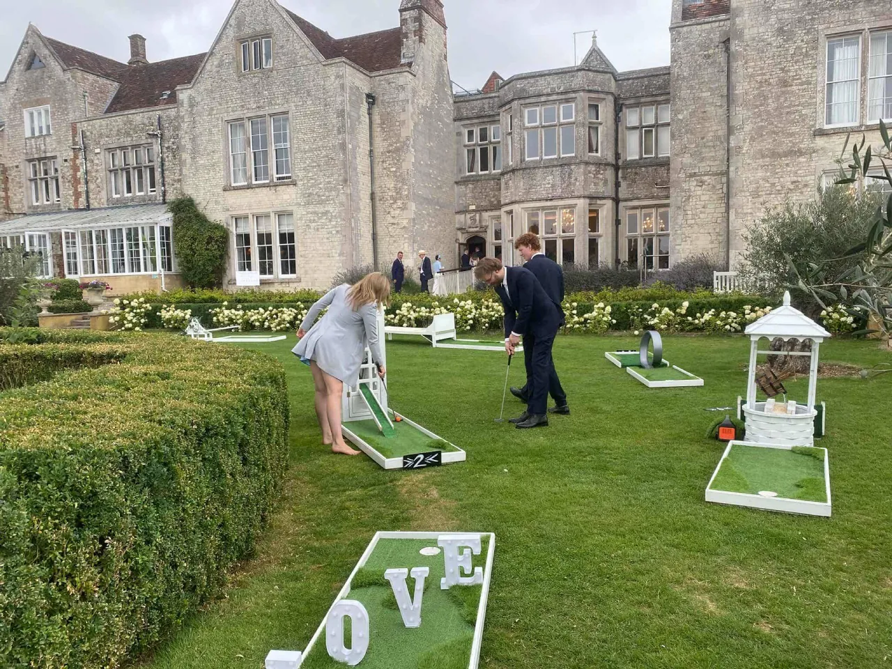Wedding guests playing mini golf on the lawn of a manor house